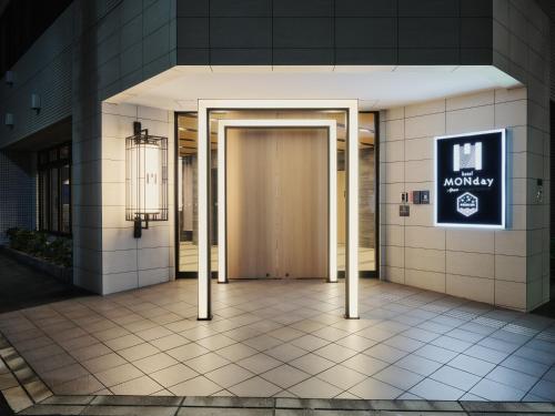 a door in a building with a sign on it at MONday Apart Premium Ginza Shintomicho in Tokyo
