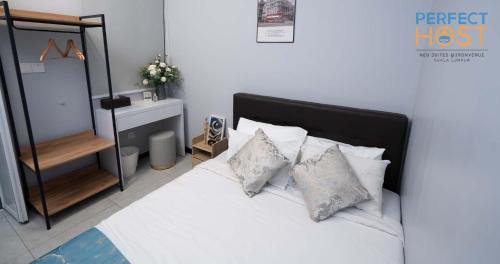 a bedroom with a bed with white sheets and pillows at Neu Suites @ 3rdNvenue by Perfect Host in Kuala Lumpur