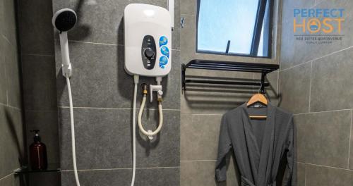 a shower head and a jacket on a rack in a bathroom at Neu Suites @ 3rdNvenue by Perfect Host in Kuala Lumpur
