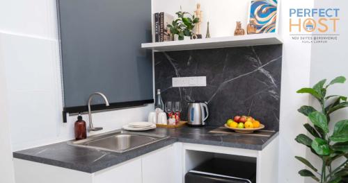 a kitchen counter with a sink and a bowl of fruit at Neu Suites @ 3rdNvenue by Perfect Host in Kuala Lumpur