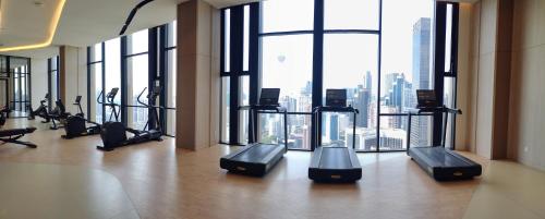 a gym with cardio equipment in a building with windows at Bukit Bintang Axon Residences 3R2B 3Queens Beds in Kuala Lumpur
