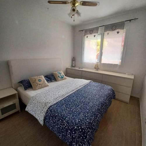 Un dormitorio con una cama con edredón azul y una ventana. en Bella, en Parque Holandes