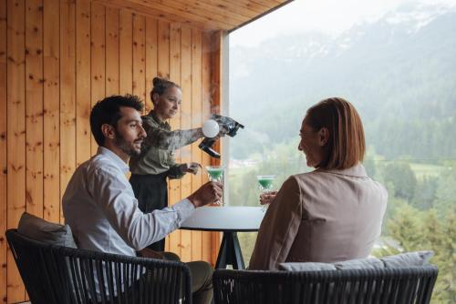 a group of people sitting around a table with a woman at Latemar - Hotel Suites Spa in Soraga