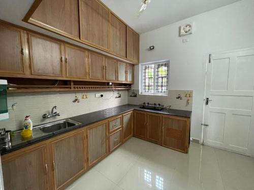 a kitchen with wooden cabinets and a sink and a door at The Dream Home Kochi in Cochin