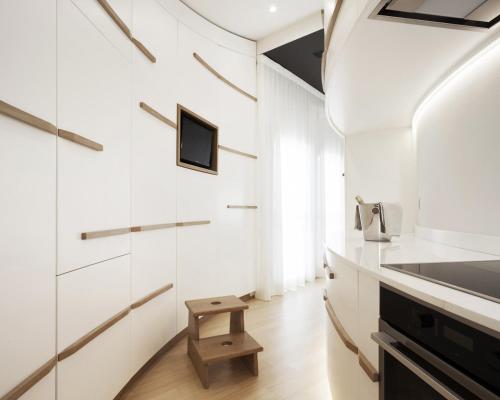 cocina con armarios blancos y TV en la pared en Canticle Lucca Luxury Apartment, en Lucca
