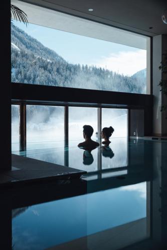 a woman sitting in a pool in front of a window at Latemar - Hotel Suites Spa in Soraga