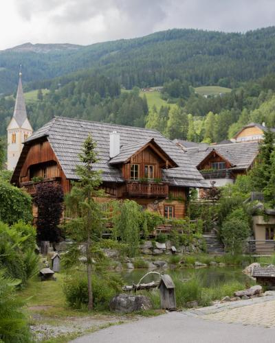 a large wooden house with a church in the background at st martin chalets in Sankt Michael im Lungau