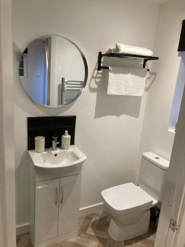 a bathroom with a white toilet and a mirror at Guest house paradiso in Great Cornard