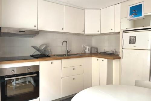 une cuisine avec des armoires blanches et un évier dans l'établissement L'auberge des Halles- Epuré & confortable, à Paris