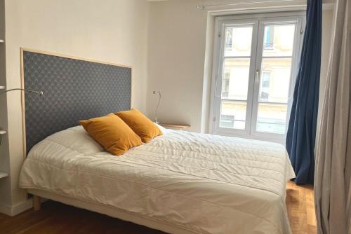 un lit avec deux oreillers dessus dans une chambre dans l'établissement L'auberge des Halles- Epuré & confortable, à Paris