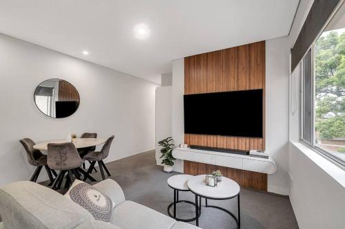 a living room with a television and a table at The 2 Bedroom Hurstville Haven in Sydney
