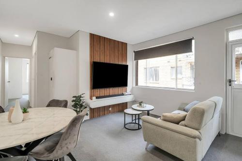 a living room with a dining room table and a tv at The 2 Bedroom Hurstville Haven in Sydney