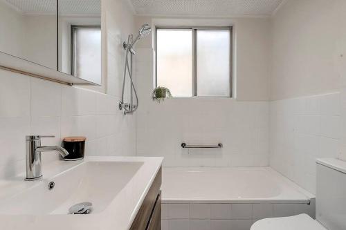 Un baño blanco con lavabo e inodoro. en The 2 Bedroom Hurstville Haven, en Sídney