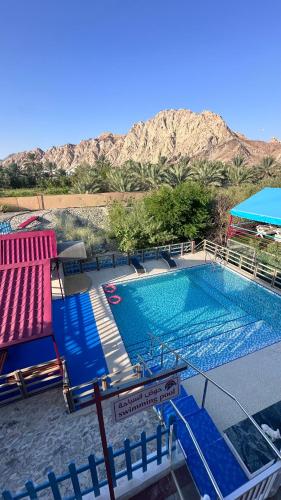 a large swimming pool with two chairs and a table at Red_Hut_Resort in Hatta