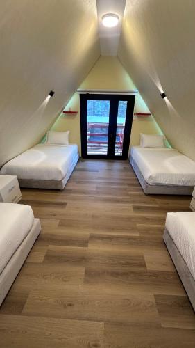 a attic room with three beds and a window at Red_Hut_Resort in Hatta