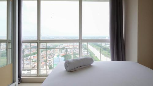 a bed with a pillow on it in front of a window at Elegant and Spacious 3BR at Bale Hinggil Apartment By Travelio in Medokanayu