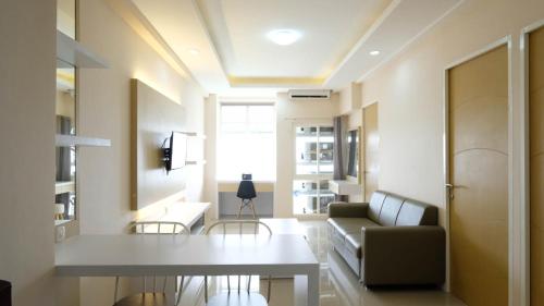 a living room with a table and a couch at Elegant and Spacious 3BR at Bale Hinggil Apartment By Travelio in Medokanayu