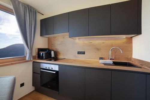 a kitchen with black cabinets and a sink and a window at Hauserhof in Lagundo