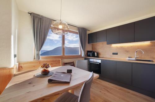 a kitchen with a wooden table and a large window at Hauserhof in Lagundo