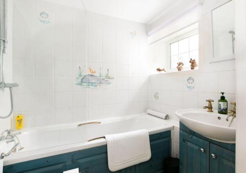 Woodcutter's Cottage - Peaceful Country Retreat! في Over Worton: حمام أبيض مع حوض استحمام ومغسلة