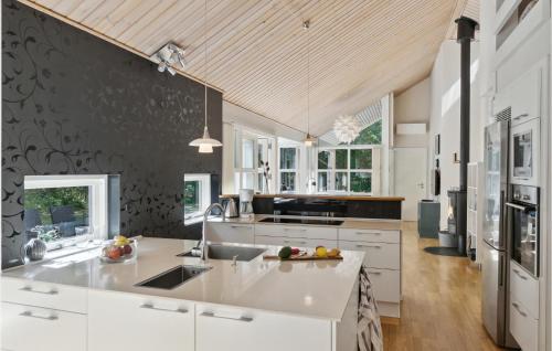 una cocina con armarios blancos y una pared negra en Rubinsøen Skovhuse, en Hasle