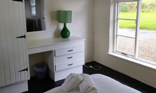 a bedroom with a bed and a dresser with a lamp at Corofin Lake Cottages in Corrofin