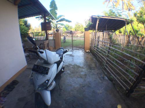 a scooter parked in a yard next to a fence at Jeges Homestay in Senggigi 