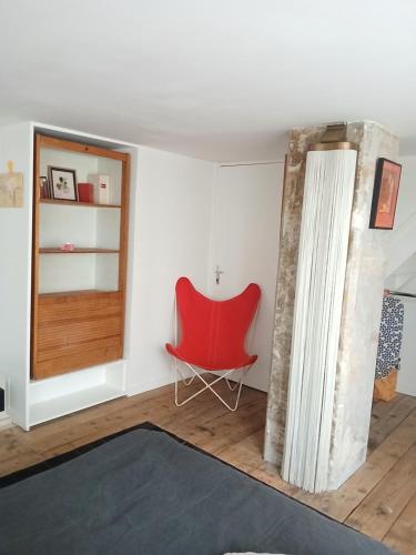 une chaise rouge assise dans une pièce avec un mur dans l'établissement Stipologic 6P 2BR, à Paris
