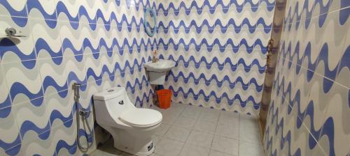 a bathroom with a toilet and a geometric wall at Spice Garden Farm house in Sultan Bathery