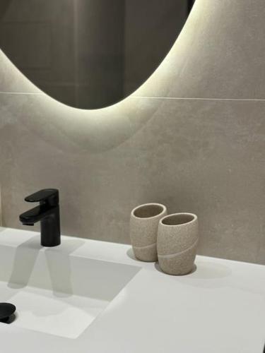 - un lavabo avec deux tasses et un robinet dans l'établissement La petite Grenille, à Antibes