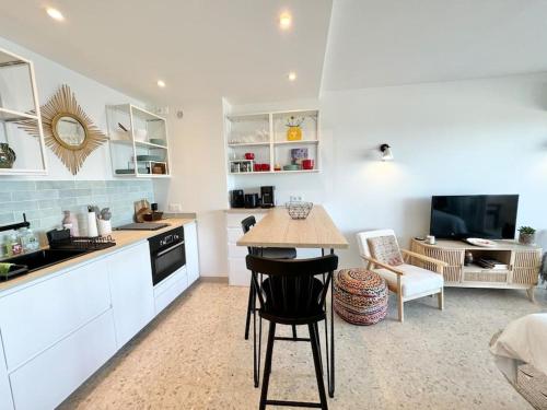 une cuisine avec des armoires blanches et une table dans une pièce dans l'établissement La petite Grenille, à Antibes