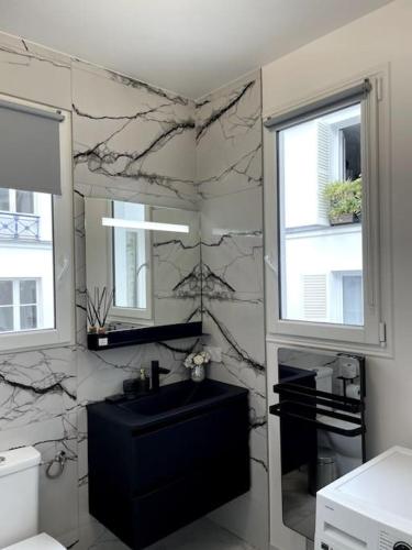 une salle de bain avec un lavabo noir et un miroir dans l'établissement Paris Luxury Family Getaway, à Paris