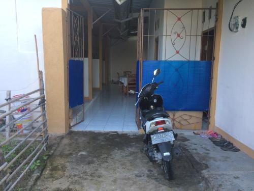 a motorcycle parked in a garage next to a door at Jeges Homestay in Senggigi 