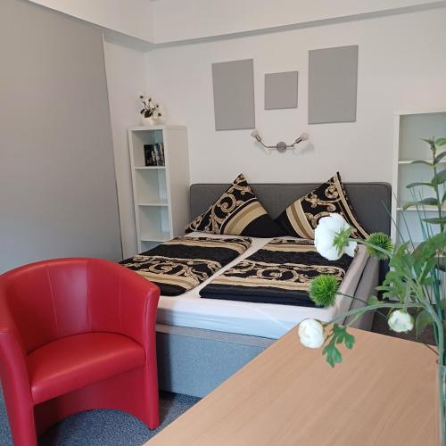 a small room with a bed and a red chair at Pension Mark in Hoyerswerda