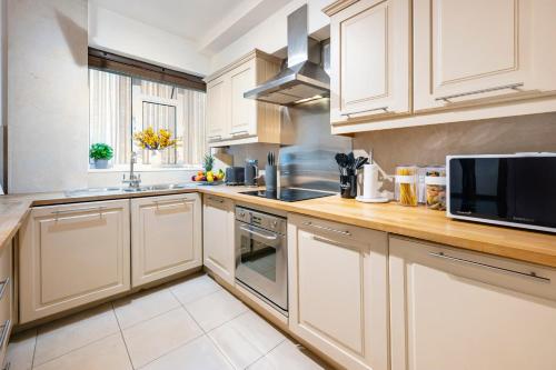 a kitchen with white cabinets and a microwave at Welcome London Buckingham Palace in London