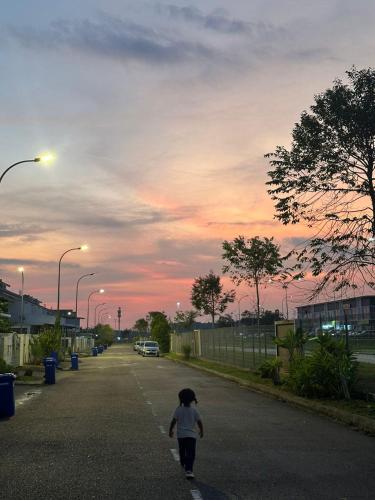 a little child walking down a street at sunset at DesaruHomestay92 in Bandar Penawar