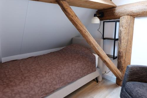 a small bed in a room with wooden beams at Bed & breakfast by Patty in Nieuw-Amsterdam