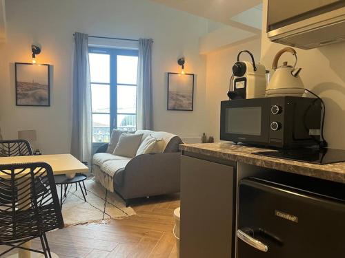 Il comprend une cuisine et un salon avec un canapé et un four micro-ondes. dans l'établissement Casaflora - Le Corner Montpellier, à Montpellier