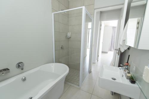 a white bathroom with a tub and a sink at Casa Bella in Summerstrand