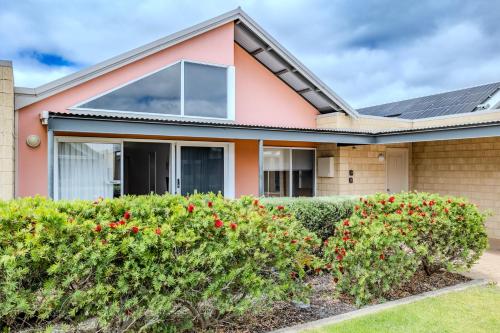 a house with red flowers in front of it at Albany Bayside by the BnB Collection in Albany