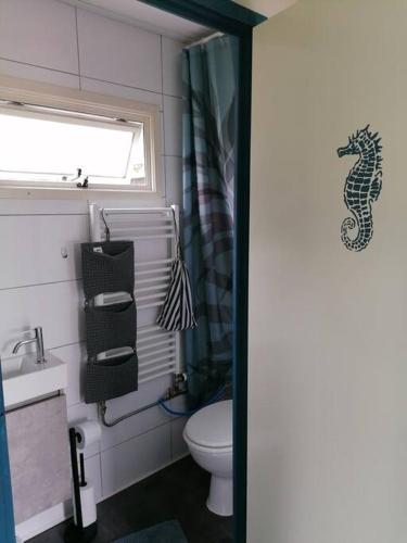 a bathroom with a seahorse shower curtain and a toilet at Tinyhouse CARPE DIEM in Dirkshorn