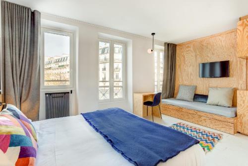 une chambre avec un lit, une télévision et des fenêtres dans l'établissement Hôtel Montholon, à Paris