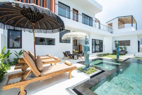 a villa with a swimming pool and a patio with chairs and an umbrella at Kamalie Bali Luxury in Tanah Lot
