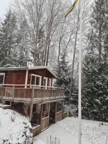 a house with a deck in the snow at A Tiny House in Norrby in Lanna-Drevviken