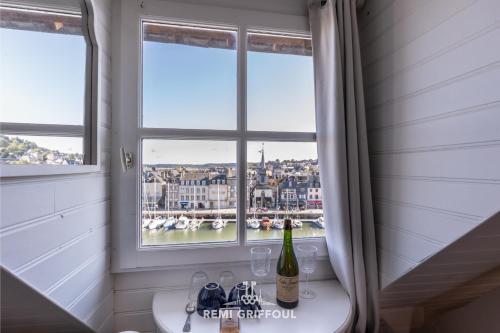 - une salle de bains avec une fenêtre et une bouteille de vin dans l'établissement Dolphin view - studio - Cozy nest with a view of the port, à Honfleur