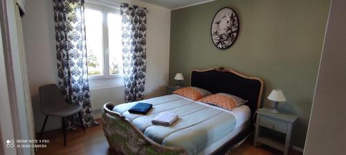 - une chambre avec un lit, une chaise et un réveil sur le mur dans l'établissement Maison avec jolie vue, 5mn à pied du centre, à Sarlat-la-Canéda