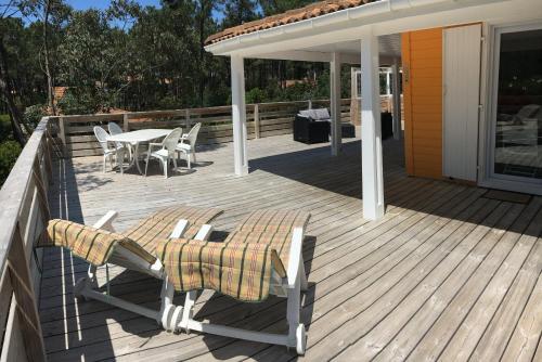 a wooden deck with a table and chairs on it at Chalet orange naturiste la Jenny in Le Porge