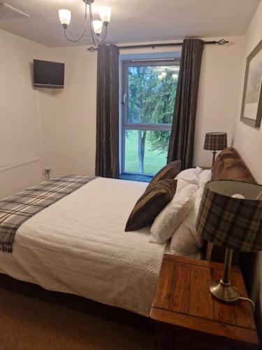 a bedroom with a large bed and a window at Glen Mor Apartment with pool on site in Fort Augustus