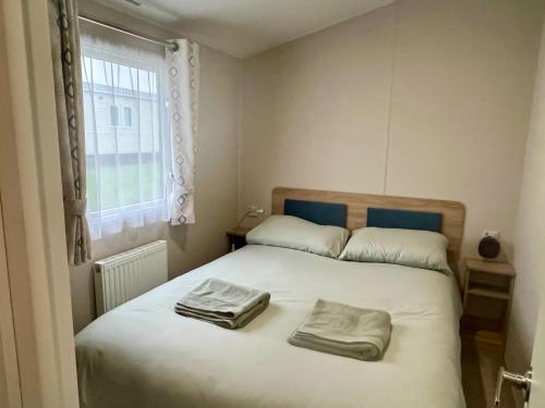 a bedroom with a bed with two towels on it at Surfside Bliss - Cayton Bay Park caravan in Scarborough