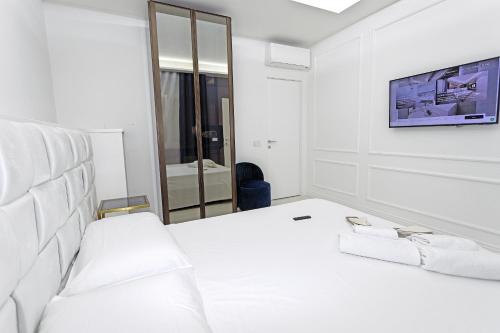 Dieses weiße Zimmer verfügt über ein Bett und einen TV an der Wand. in der Unterkunft Luxury apartment-Corso Malta by Alux38 in Neapel